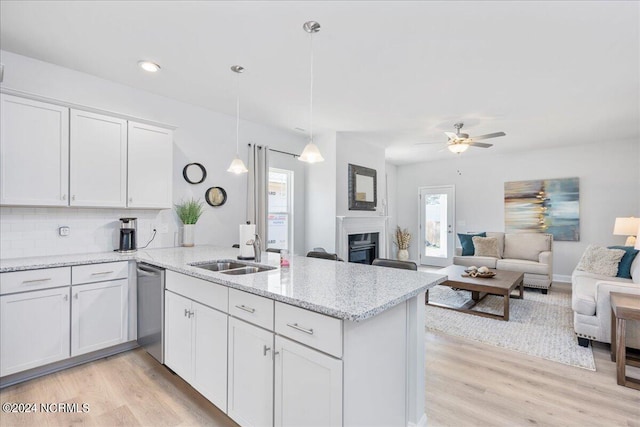 kitchen with light hardwood / wood-style flooring, decorative light fixtures, kitchen peninsula, sink, and white cabinets