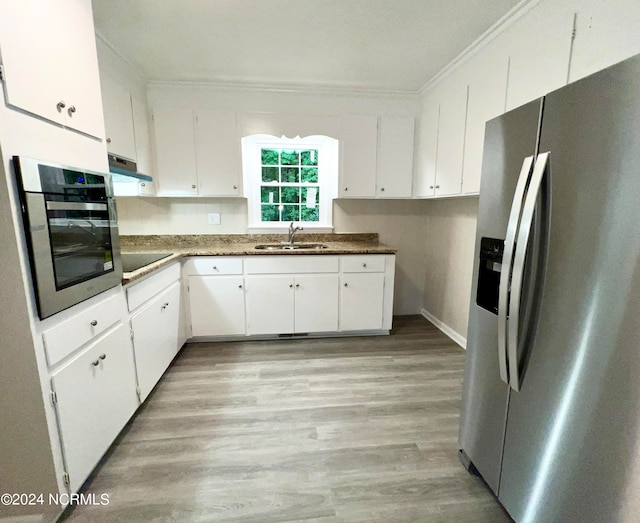 kitchen featuring stainless steel appliances, white cabinetry, light hardwood / wood-style floors, and sink