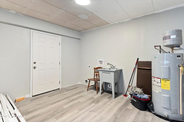 basement featuring water heater and light hardwood / wood-style floors