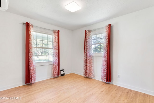 spare room with a textured ceiling and light hardwood / wood-style flooring