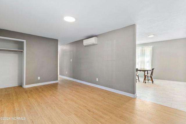 interior space with light wood-type flooring, a closet, and a wall unit AC