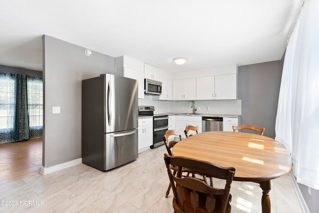 kitchen with white cabinets, appliances with stainless steel finishes, tasteful backsplash, and sink