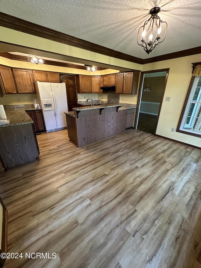 kitchen featuring a chandelier, light wood-style flooring, a peninsula, white refrigerator with ice dispenser, and ornamental molding