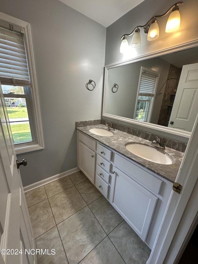 full bathroom with tile patterned flooring, a sink, baseboards, and double vanity