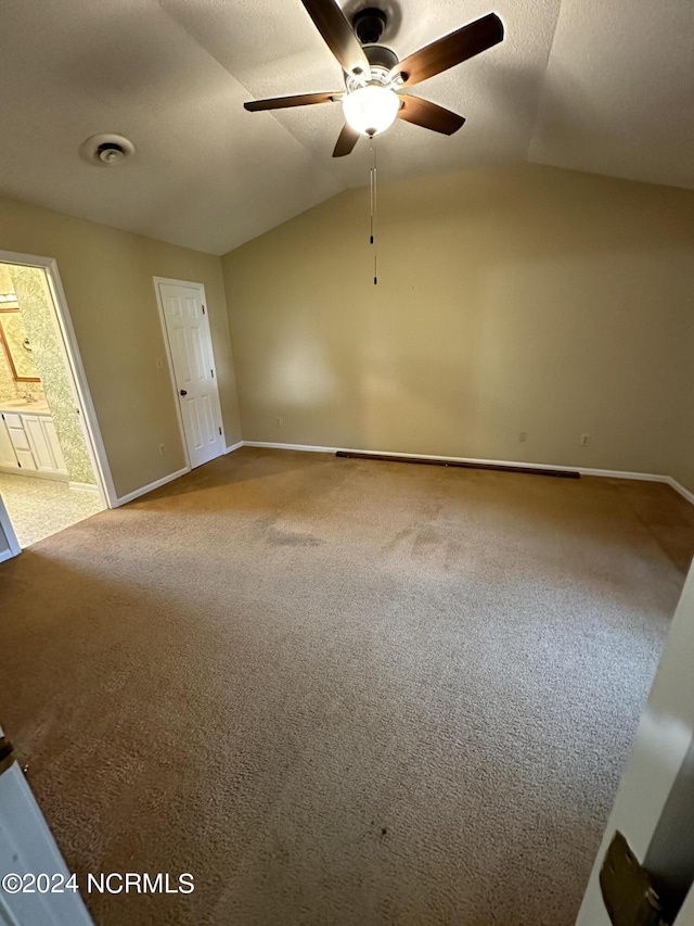 carpeted empty room featuring lofted ceiling, a textured ceiling, and baseboards