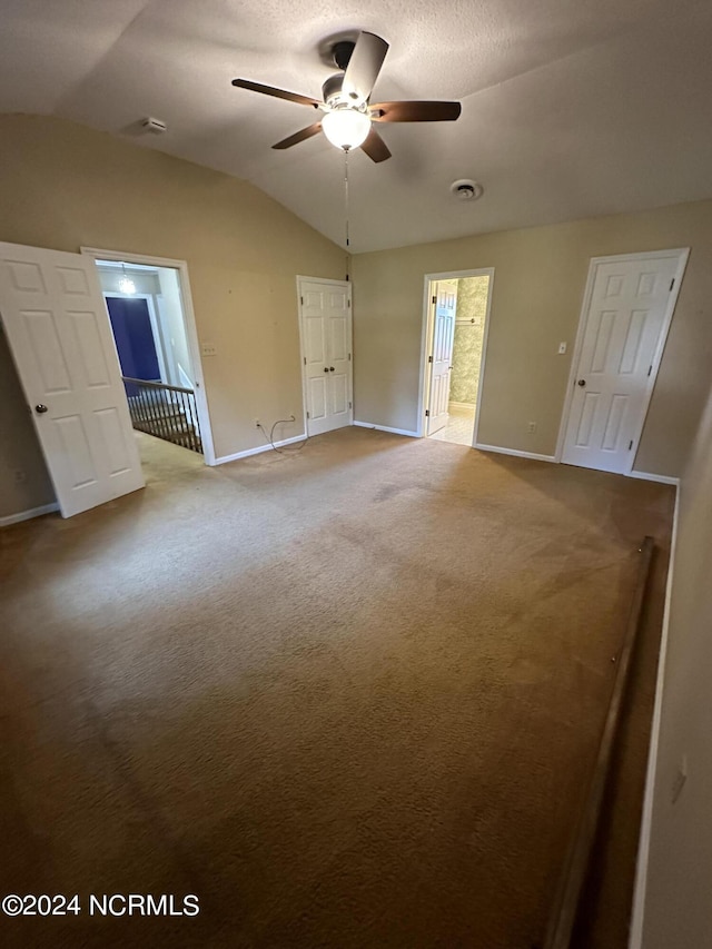 carpeted empty room featuring lofted ceiling, baseboards, visible vents, and a ceiling fan