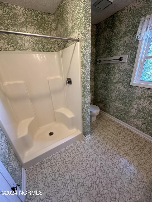 full bathroom with toilet, wallpapered walls, baseboards, and walk in shower