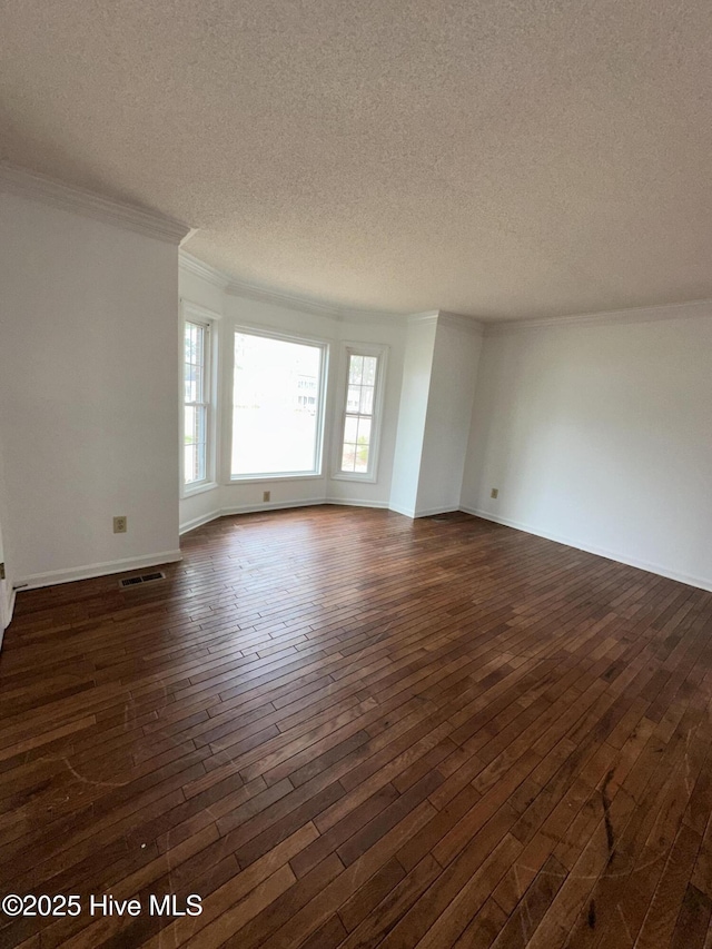 spare room with a textured ceiling, dark wood-style flooring, visible vents, and crown molding