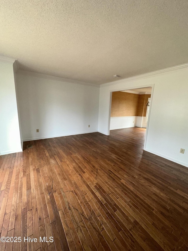 empty room with crown molding, dark wood finished floors, a textured ceiling, and baseboards