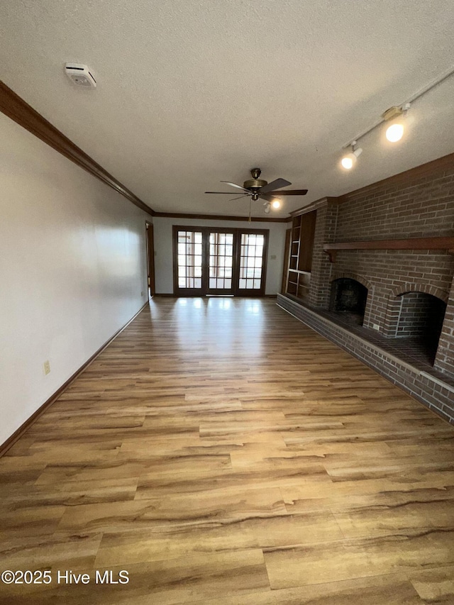 unfurnished living room featuring a fireplace, ornamental molding, a textured ceiling, and wood finished floors