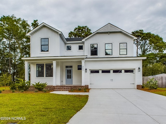 modern farmhouse featuring a garage, a front yard, and a porch