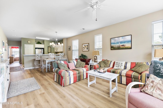 living room with ceiling fan with notable chandelier, light hardwood / wood-style floors, and plenty of natural light