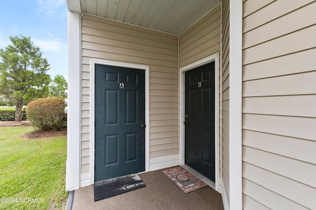 view of exterior entry featuring a lawn