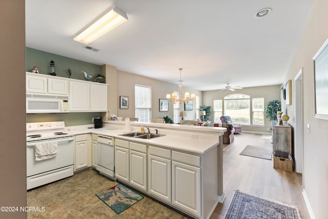 kitchen featuring sink, kitchen peninsula, white appliances, decorative light fixtures, and hardwood / wood-style floors