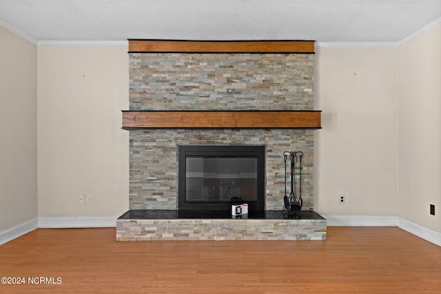 room details with wood-type flooring, a stone fireplace, a textured ceiling, and crown molding