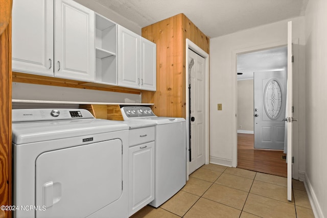 washroom featuring cabinets, washer and clothes dryer, light tile patterned floors, and a textured ceiling