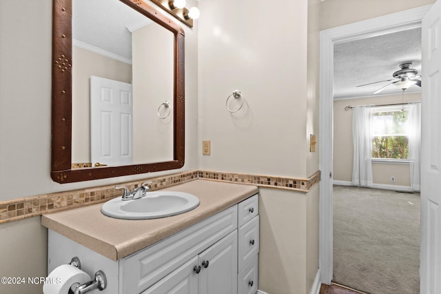 bathroom featuring a textured ceiling, crown molding, vanity, and ceiling fan