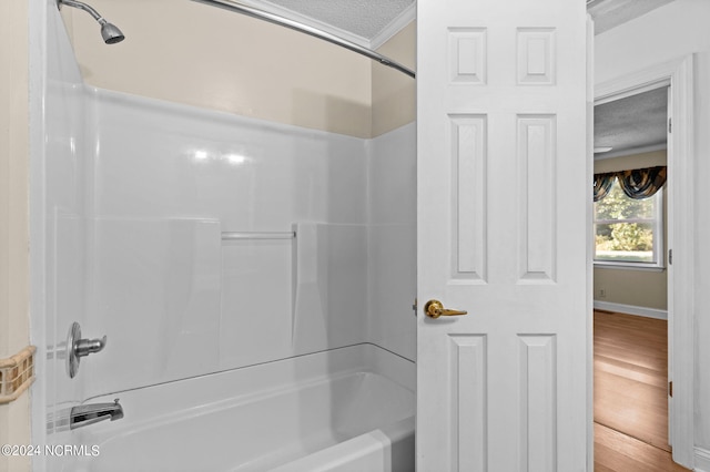 bathroom with a textured ceiling, bathing tub / shower combination, hardwood / wood-style floors, and crown molding