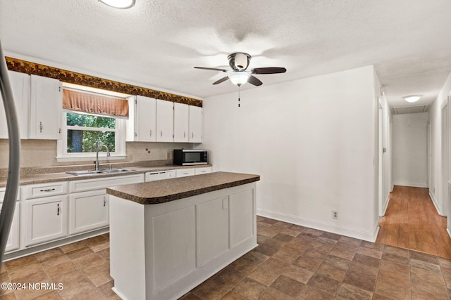 kitchen with white cabinets, ceiling fan, a center island, and sink