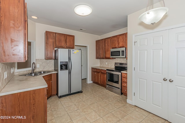 kitchen with sink, pendant lighting, light tile patterned floors, appliances with stainless steel finishes, and tasteful backsplash