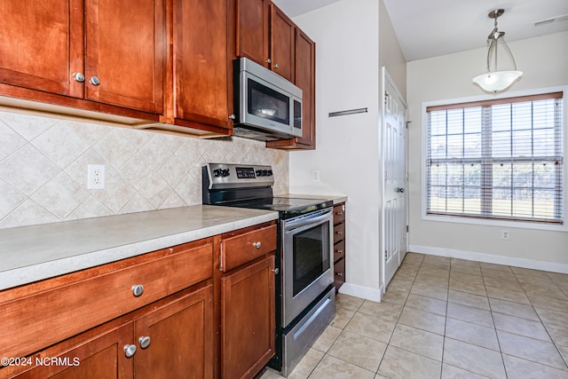 kitchen with appliances with stainless steel finishes, decorative backsplash, light tile patterned floors, and pendant lighting