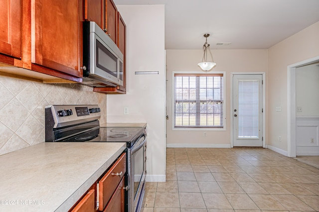 kitchen featuring stainless steel appliances, decorative backsplash, light tile patterned floors, and decorative light fixtures