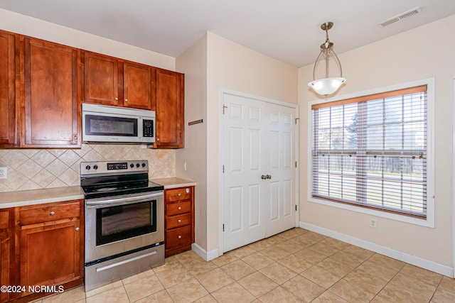 kitchen featuring decorative backsplash, decorative light fixtures, stainless steel appliances, and light tile patterned floors