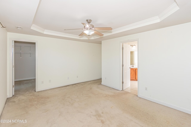 empty room featuring light carpet, a raised ceiling, and ceiling fan