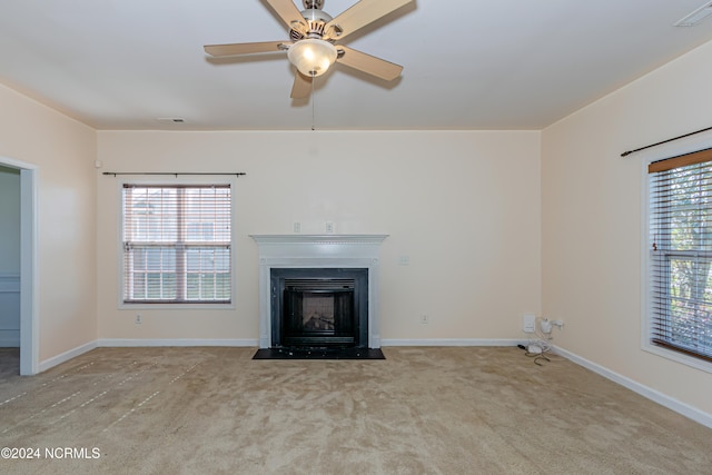 unfurnished living room featuring ceiling fan, a healthy amount of sunlight, and light colored carpet