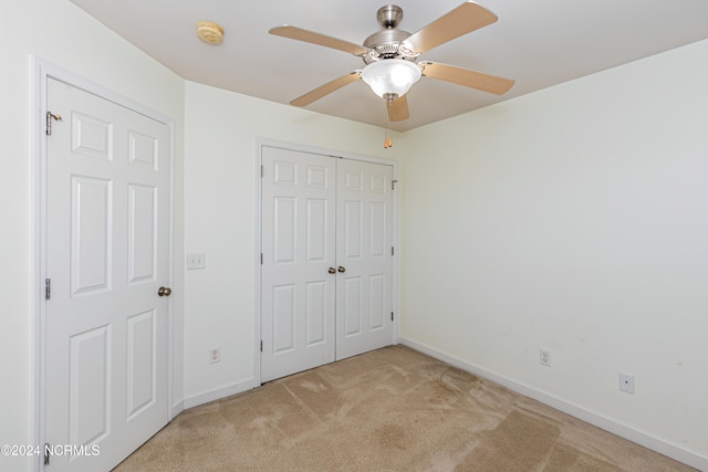 unfurnished bedroom featuring light carpet, a closet, and ceiling fan