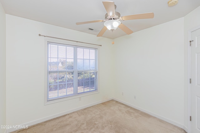 spare room featuring ceiling fan, a wealth of natural light, and light colored carpet