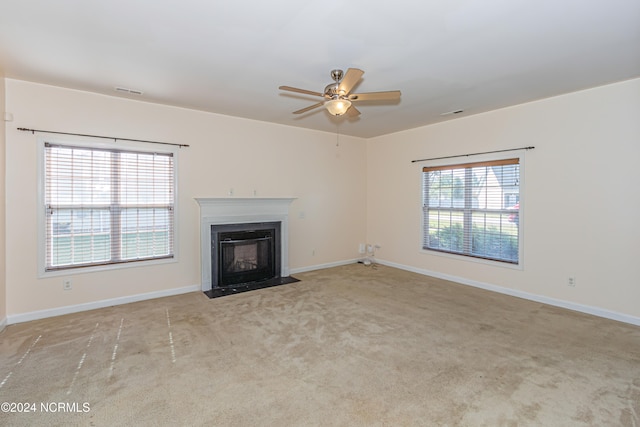 unfurnished living room with a wealth of natural light, light colored carpet, and ceiling fan