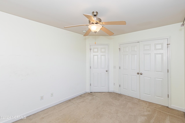 unfurnished bedroom with a closet, light colored carpet, and ceiling fan