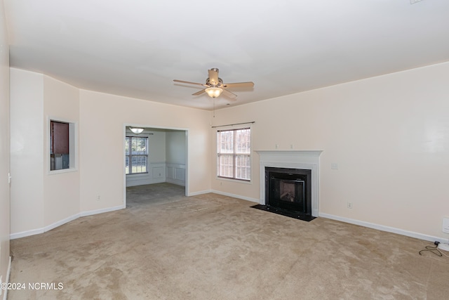 unfurnished living room with light colored carpet and ceiling fan