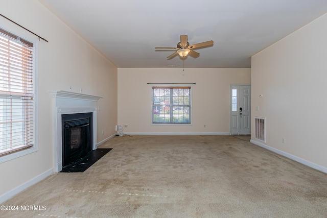 unfurnished living room with light colored carpet and ceiling fan