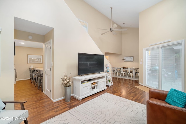 living room featuring dark wood-type flooring, high vaulted ceiling, and ceiling fan