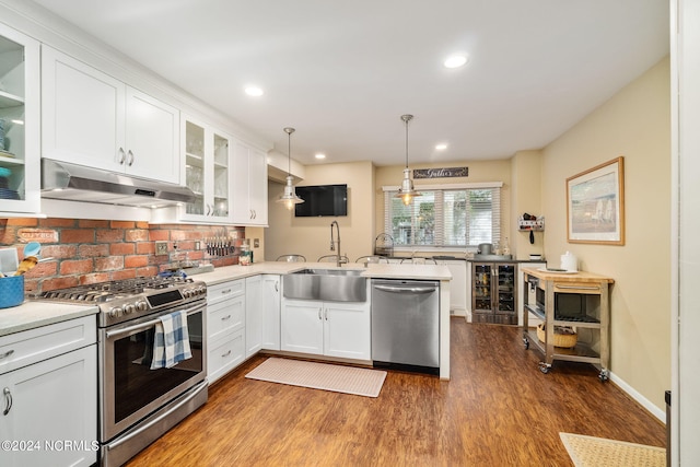 kitchen featuring pendant lighting, hardwood / wood-style flooring, stainless steel appliances, and white cabinets