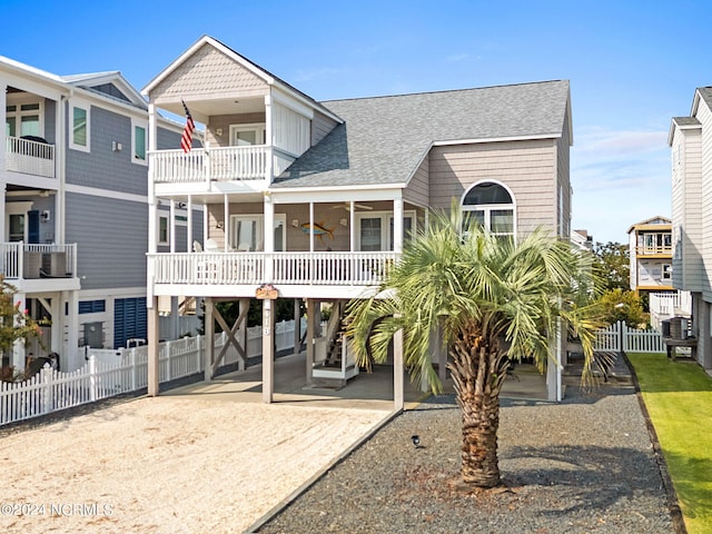 exterior space featuring a shingled roof, fence, a balcony, a carport, and a patio