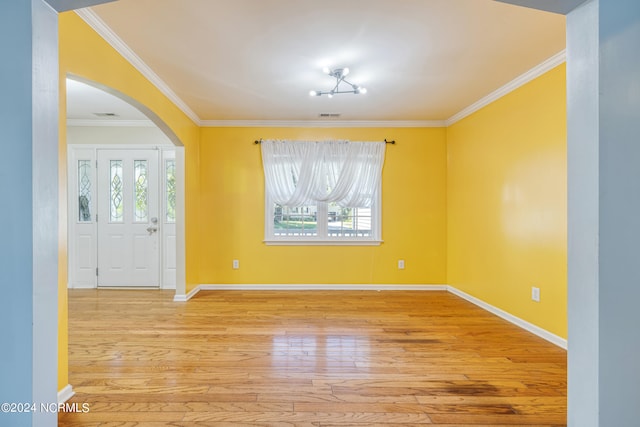 empty room featuring a chandelier, crown molding, and light hardwood / wood-style flooring