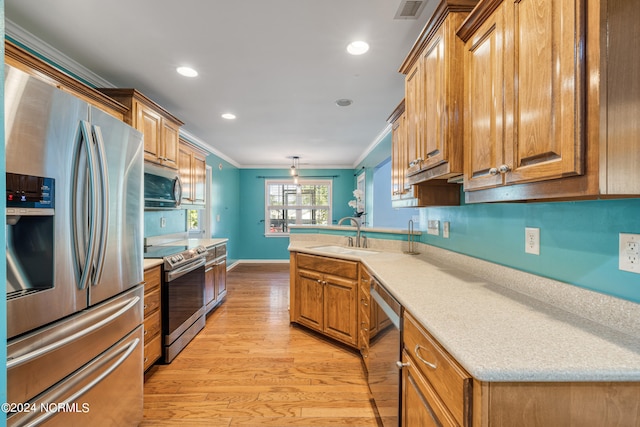 kitchen with crown molding, light hardwood / wood-style flooring, decorative light fixtures, appliances with stainless steel finishes, and sink