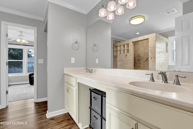 bathroom with ceiling fan, vanity, a tile shower, hardwood / wood-style flooring, and crown molding