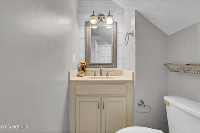 bathroom with vaulted ceiling, vanity, toilet, and a textured ceiling