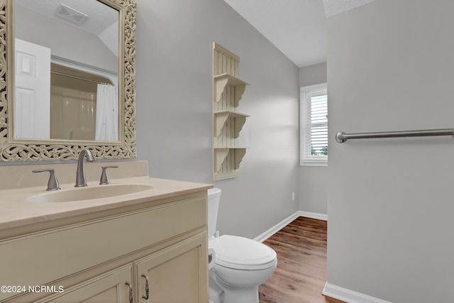 bathroom featuring vaulted ceiling, vanity, a textured ceiling, toilet, and hardwood / wood-style floors