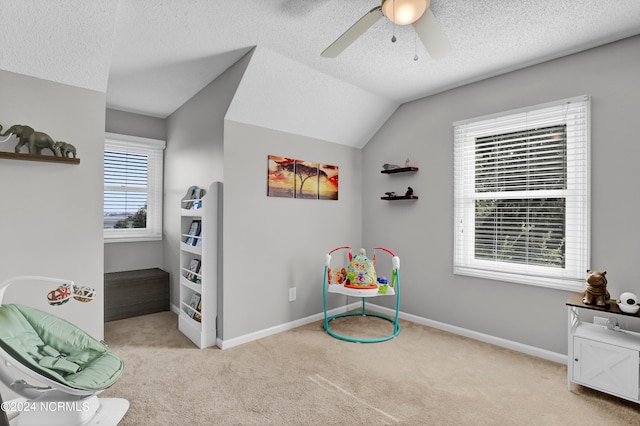 playroom with lofted ceiling, ceiling fan, light colored carpet, and a textured ceiling