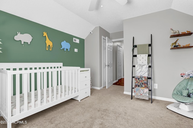 bedroom with light colored carpet, vaulted ceiling, ceiling fan, and a nursery area