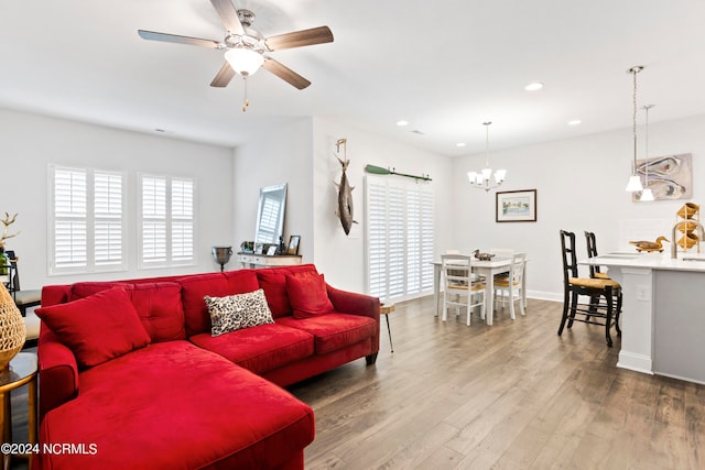 living room with hardwood / wood-style flooring and ceiling fan with notable chandelier