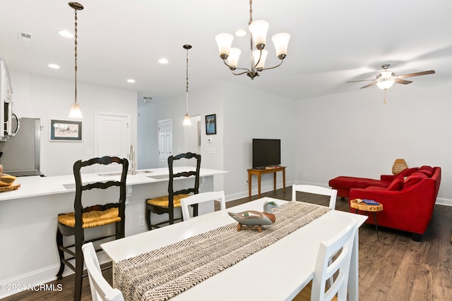 dining room with ceiling fan with notable chandelier and dark hardwood / wood-style floors