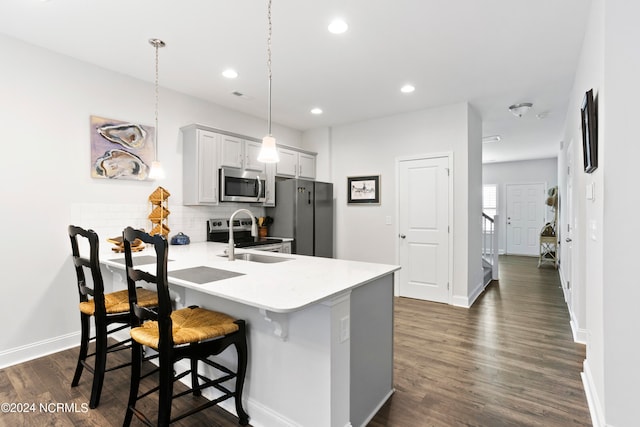 kitchen with appliances with stainless steel finishes, a breakfast bar, dark hardwood / wood-style flooring, decorative light fixtures, and sink