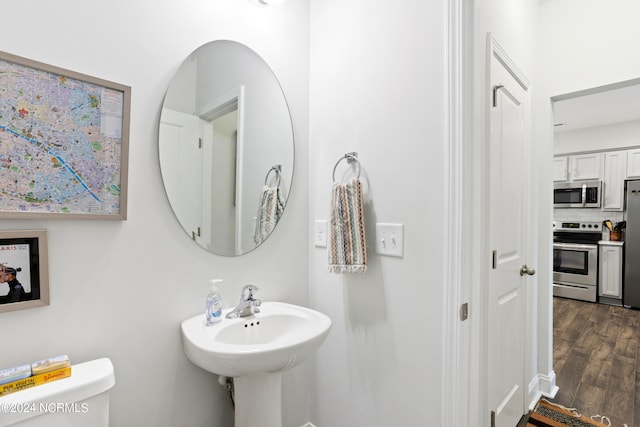 bathroom featuring wood-type flooring, tasteful backsplash, and toilet