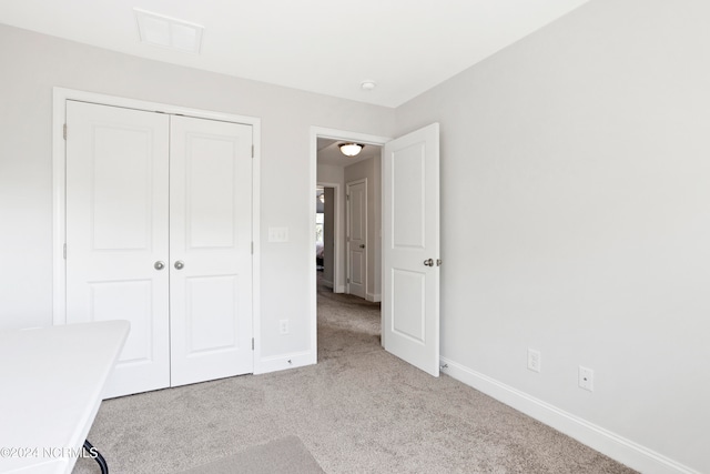 unfurnished bedroom with light colored carpet and a closet